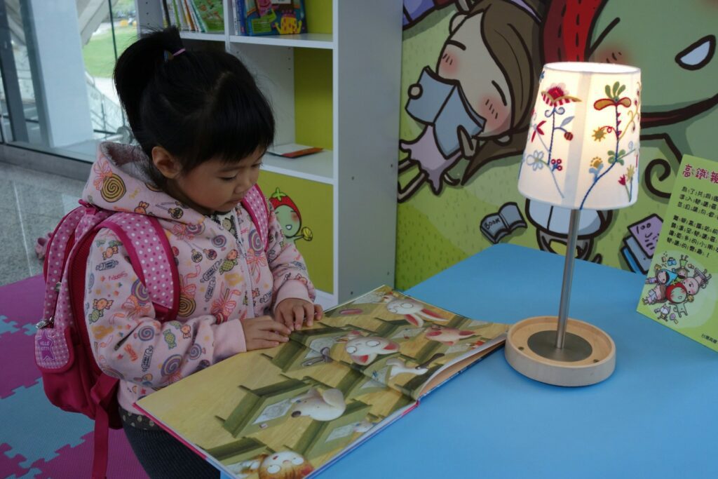 A young girl reads a book at a table.